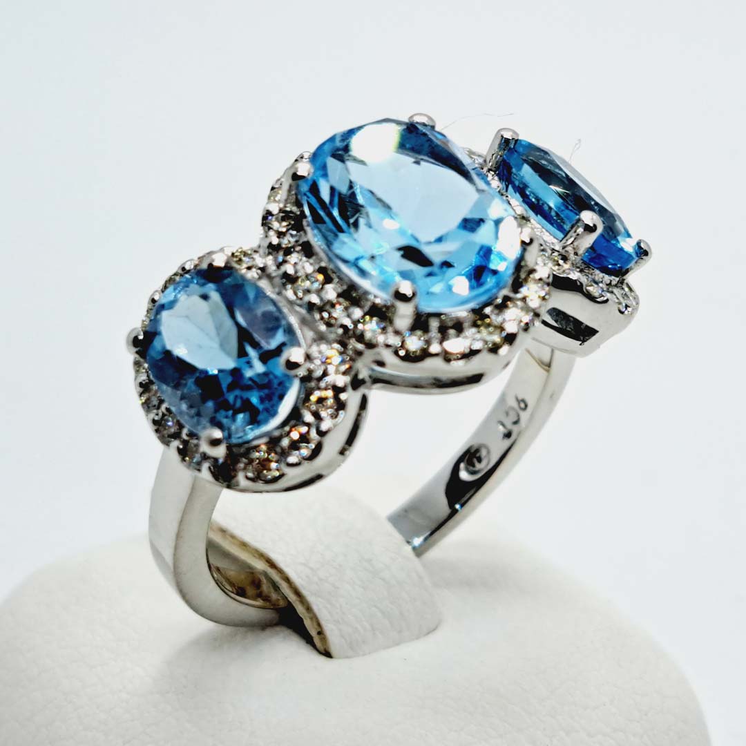 9kt White Gold Ring with Oval Cut Sky Blue Topaz Trilogy & Diamond Halos